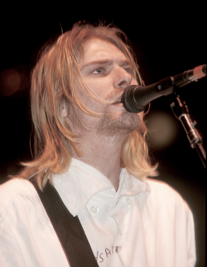 Kurt Cobain singing into a microphone during a live performance, with focus on forensic evidence discussions.