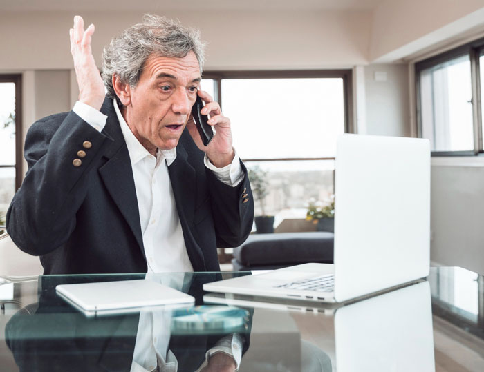 Frustrated man on phone in modern office, representing scammer regretting $2k laundering attempt with hotel receptionist. Frustrated man on phone in modern office, representing scammer regretting $2k laundering attempt with hotel receptionist.