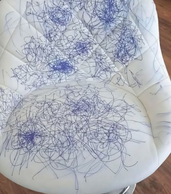 White upholstered chair covered in blue pen scribbles and doodles, a messy surprise — woke up expecting a normal day