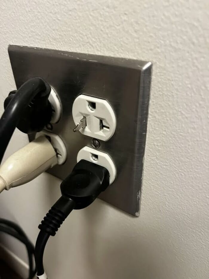 Wall outlet with a broken plug prong stuck in the top socket and several cords plugged in, people who woke up