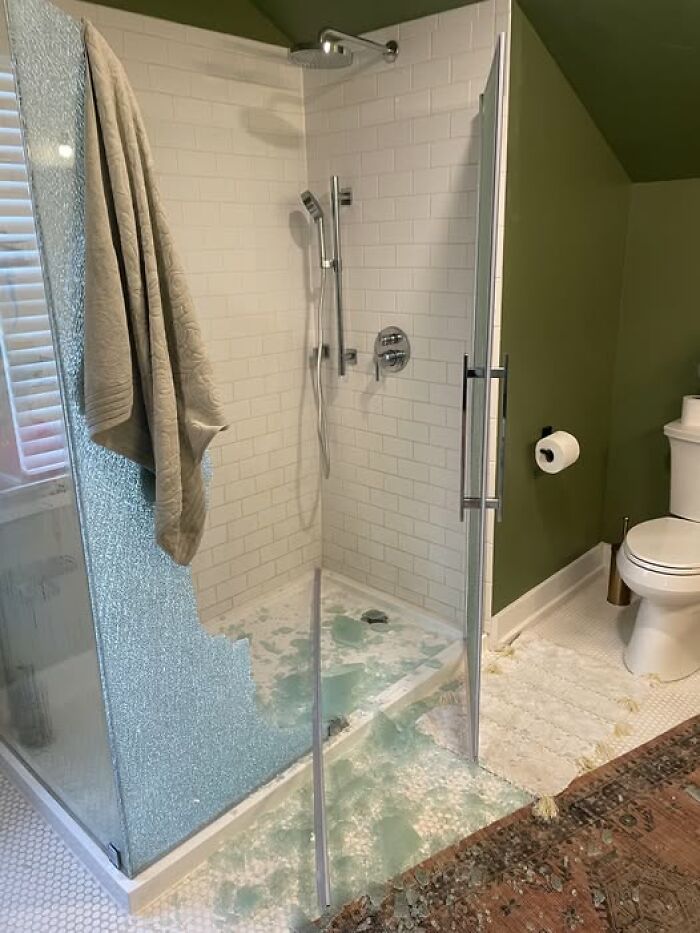 Shattered glass shower door, bathroom floor covered in shards and towel hanging, woke up to a broken shower