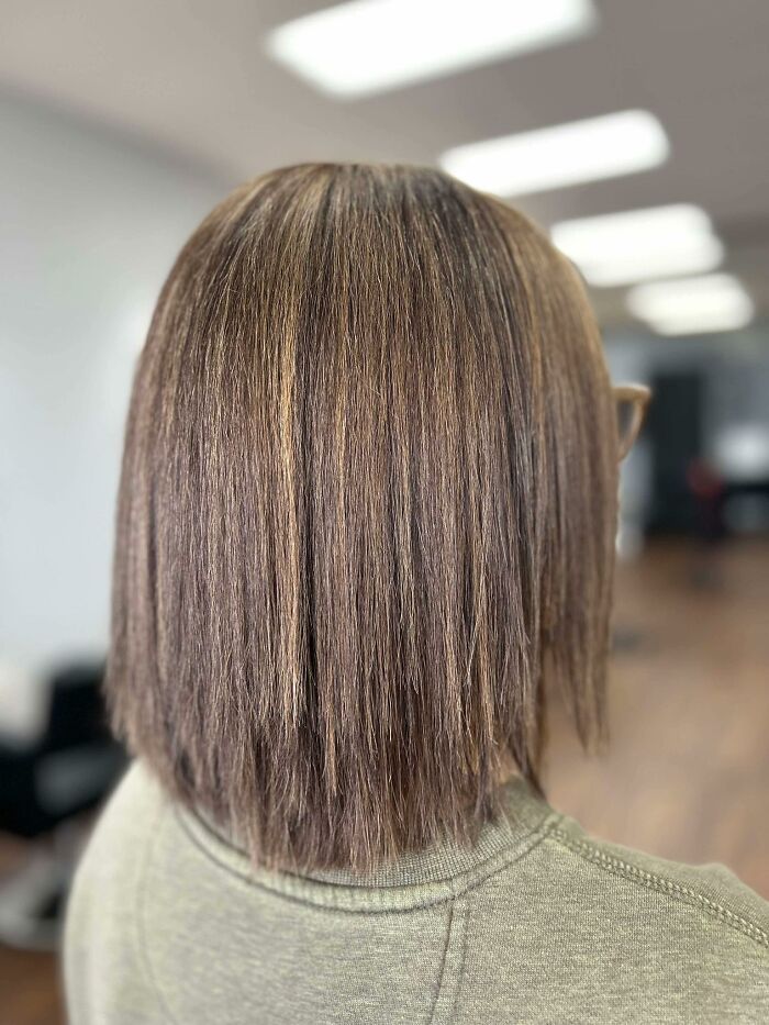 Back view of a straight, uneven brown hairstyle in a salon setting, showcasing one of the disastrous hairstyles.