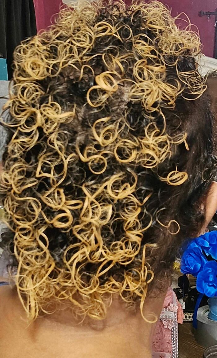 Tightly curled hair dyed unevenly blonde and black, showcasing one of the most disastrous hairstyles on an individual.