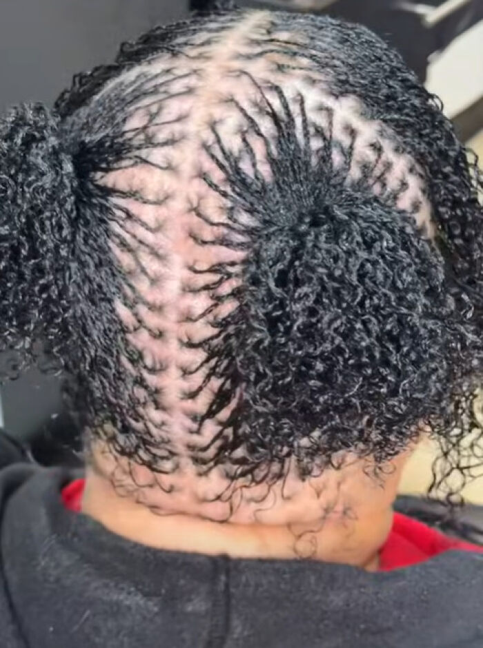 Close-up of a person’s head with a disastrous hairstyle featuring unevenly braided and curly hair sections.
