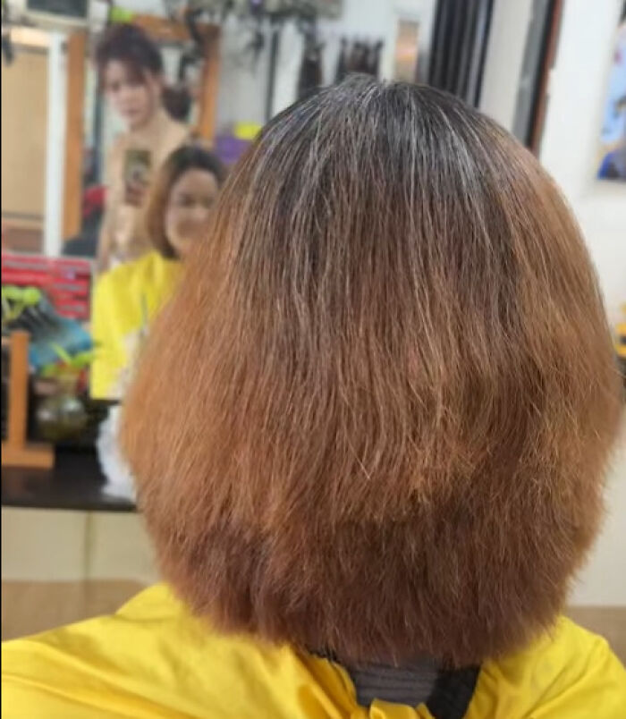 Disastrous hairstyle with uneven texture and awkward shape viewed from the back in a salon setting.