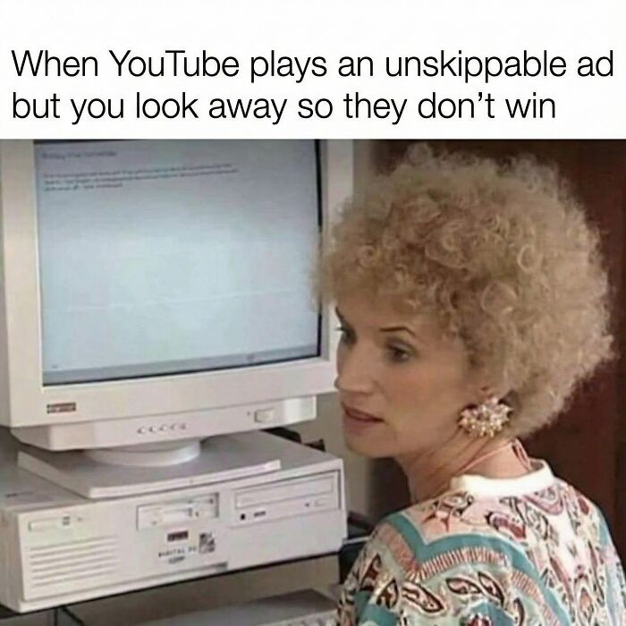 Woman with curly hair looking away from an old computer screen, illustrating a funny meme about skipping unskippable ads.