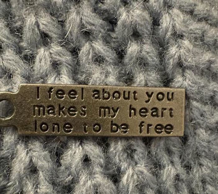 Metal tag with confusing text placed on a gray knitted fabric, illustrating people breaking their brain trying to understand.