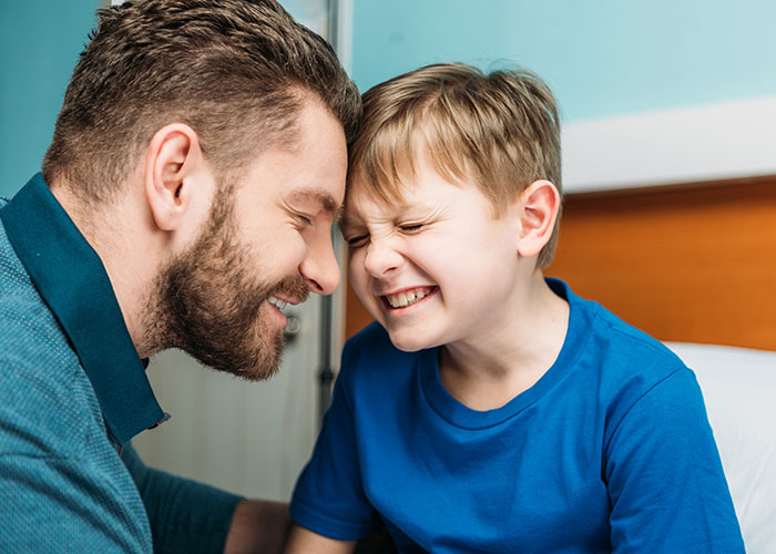 Man and young boy smiling and touching foreheads in a playful moment highlighting a woman's award winning act in court. Man and young boy smiling and touching foreheads in a playful moment highlighting a woman's award winning act in court.