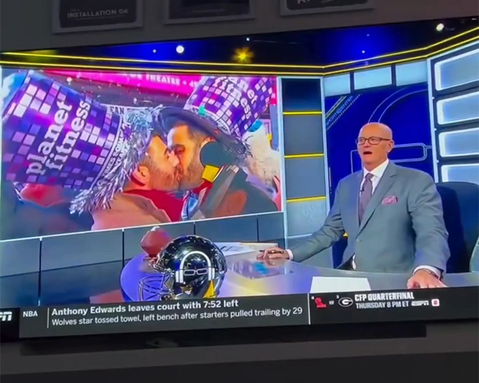 ESPN host on set reacting while a large screen shows a gay couple kissing at a New Year’s Eve celebration ESPN host on set reacting while a large screen shows a gay couple kissing at a New Year’s Eve celebration