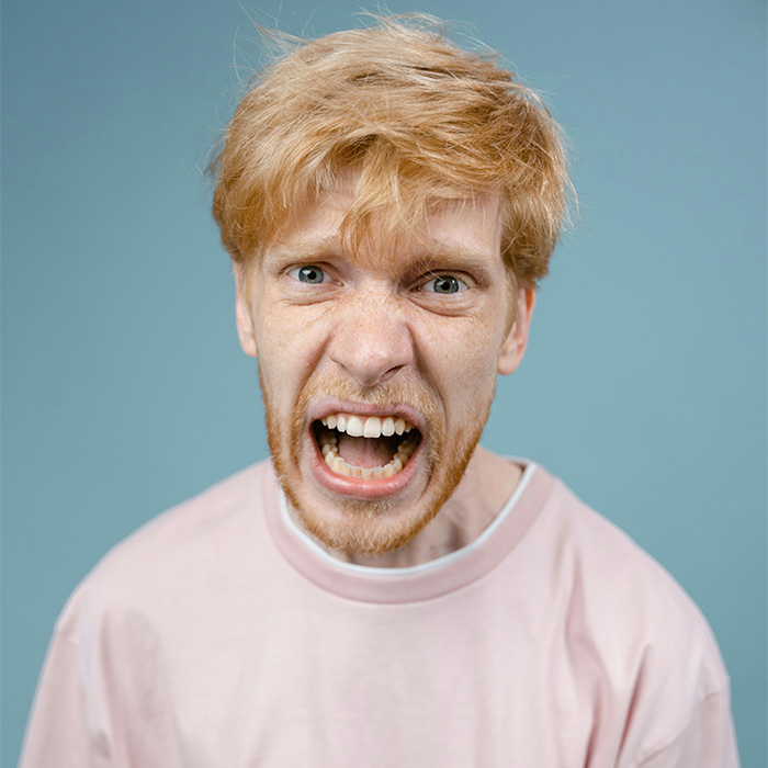 Young man with red hair showing anger in a pink shirt, representing the male Karen Gen Z has named.