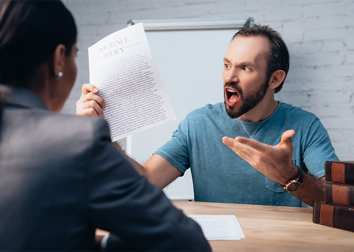 Man angrily holding a paper while arguing with a woman, illustrating a male Karen stereotype in a tense setting.