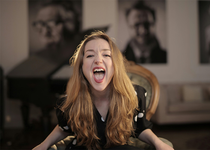 Young woman with long hair laughing energetically indoors, representing Gen Z reactions to the male Karen name debate.