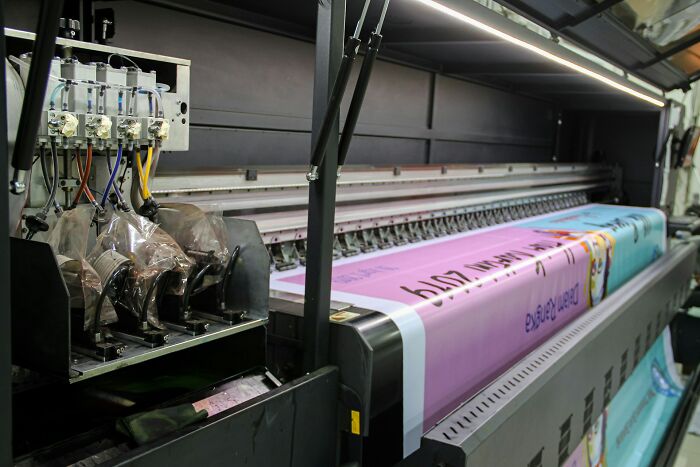 Large industrial printer in action with vibrant colors, revealing dramatic behind scenes of people in boring industries.