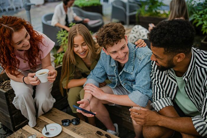 Group of friends smiling and sharing a moment outdoors, discussing adult goals and life experiences together.