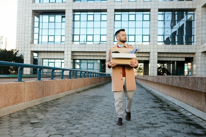 Man carrying box of belongings outside office building symbolizing moments people realized they no longer wanted to work at job.