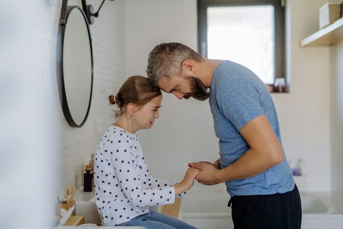 Father and daughter sharing a tender moment in a bathroom after discovering surprising DNA test results together.