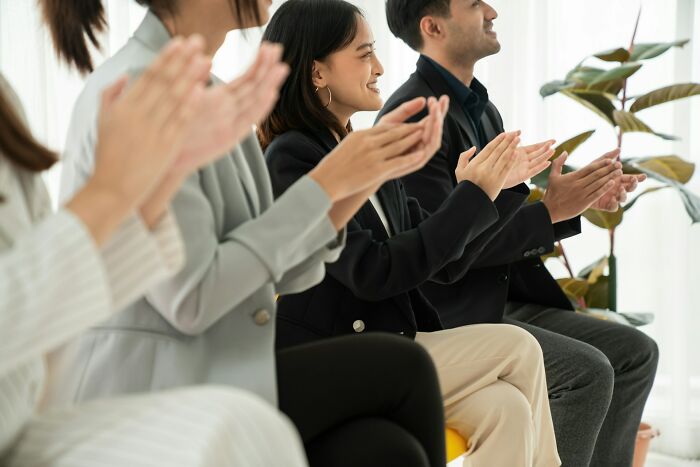 Group of former cult members sitting and clapping during a support meeting in a bright, casual indoor setting.