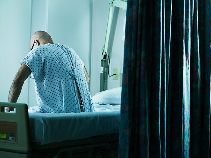 Patient sitting on hospital bed in a gown, highlighting concerns about a doctor doing something unethical with a patient.
