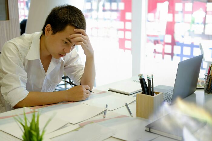 Young man stressed at his desk surrounded by paperwork, reflecting on moments they no longer wanted to work and quit.