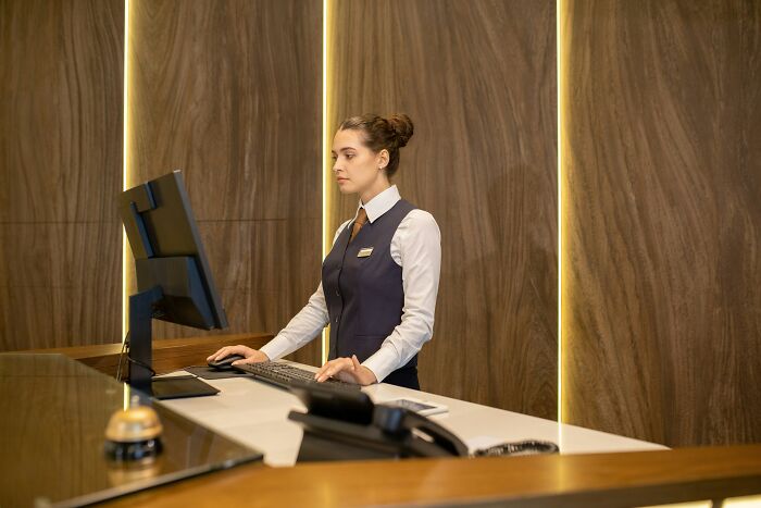 Receptionist at a front desk looking stressed while working on a computer, illustrating moments people quit their job.