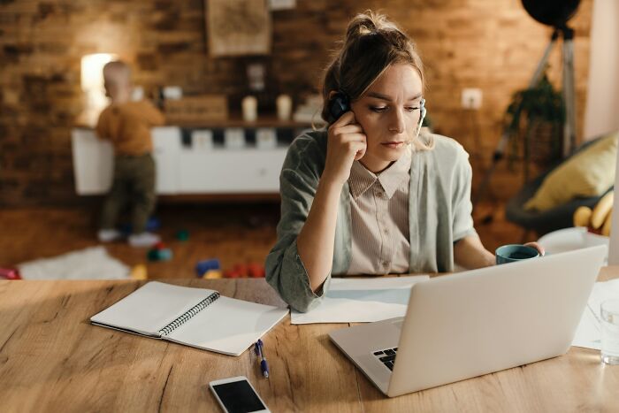 Woman focused on laptop at a wooden table with notebook and phone, highlighting common adult goals and challenges.