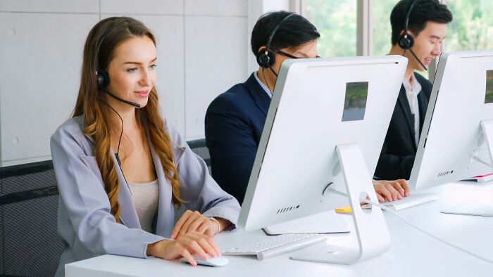 Customer service team wearing headsets, working on computers, handling ridiculous moments and prank-related calls.