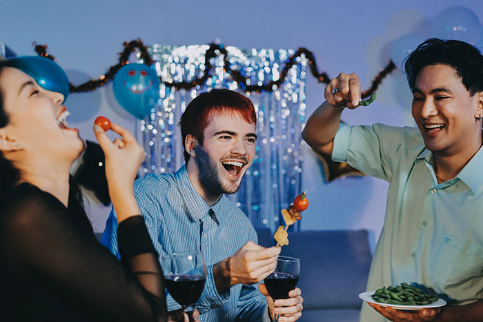Three friends enjoying food and drinks at a party while a guy suspects his GF is cheating with his roommate.