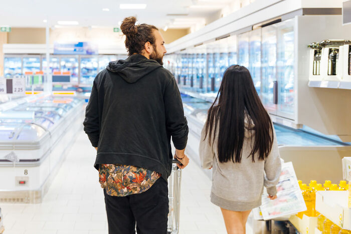 Man and woman shopping in grocery store aisle, illustrating food shopping triggers and coping challenges. Man and woman shopping in grocery store aisle, illustrating food shopping triggers and coping challenges.