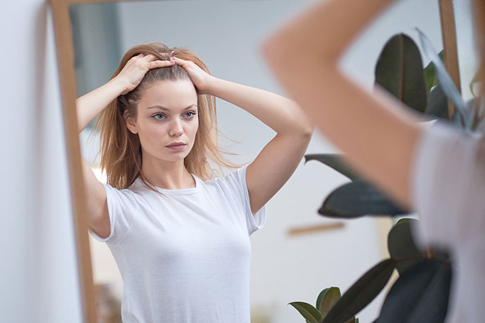 Young gifted woman with potential looking at herself in the mirror, reflecting on life and achievements.