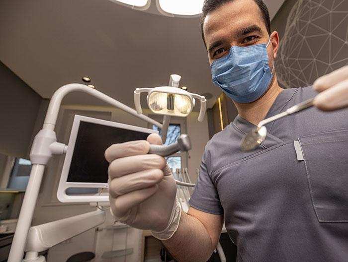 Dentist wearing a blue mask and gloves holding dental tools in a clinic, symbolizing gifted kids with potential in careers.