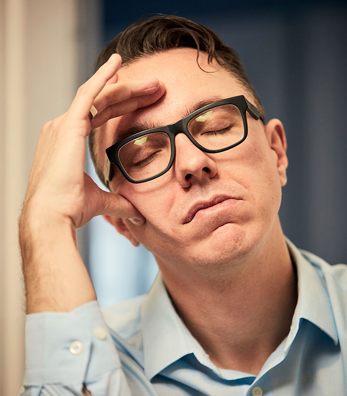 Close-up of a stressed man with glasses reflecting on potential, relating to gifted kids and their life achievements.