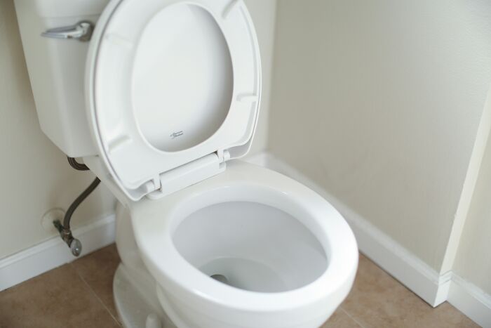 White toilet with open lid in a plain bathroom, symbolizing petty fights during the Christmas period among couples.