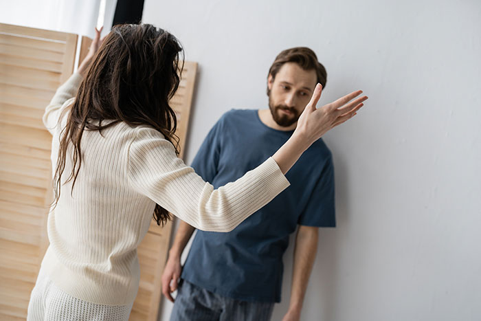 Woman arguing with boyfriend who looks emasculated as she gestures while fixing things in their home. Woman arguing with boyfriend who looks emasculated as she gestures while fixing things in their home.