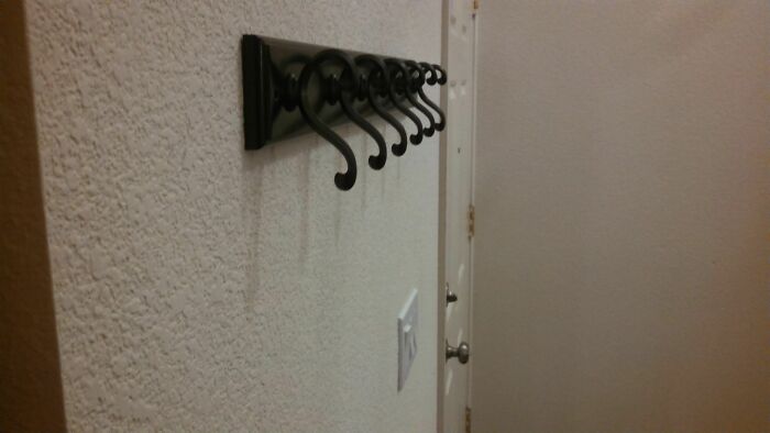 Wall hooks installed upside down on a textured wall, showcasing a clear DIY fail that needs to be shamed.