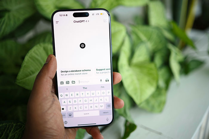 Person holding smartphone with ChatGPT open, using AI as a personal relationship coach in a casual setting. Person holding smartphone with ChatGPT open, using AI as a personal relationship coach in a casual setting.