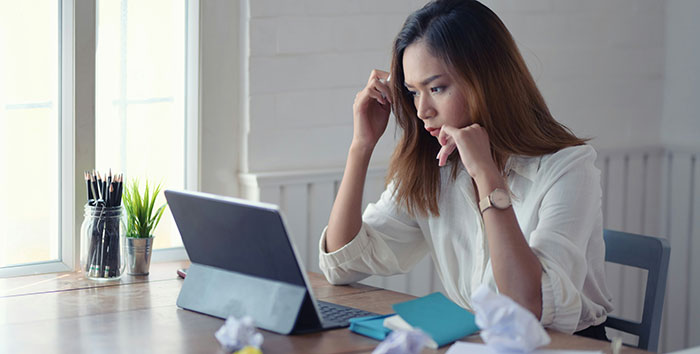 Woman using AI as her personal relationship coach on tablet, looking concerned while sitting at a desk with crumpled papers. Woman using AI as her personal relationship coach on tablet, looking concerned while sitting at a desk with crumpled papers.