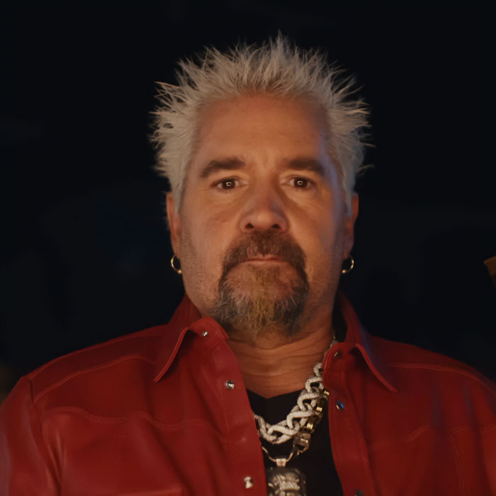 Guy Fieri in a red jacket with spiky blonde hair, showcasing his 58th birthday glow-up and new look. Guy Fieri in a red jacket with spiky blonde hair, showcasing his 58th birthday glow-up and new look.