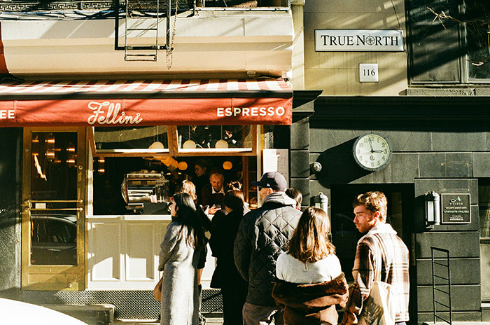 People waiting in line outside a coffee shop, illustrating coffee line skipping and patrons competing in the morning. People waiting in line outside a coffee shop, illustrating coffee line skipping and patrons competing in the morning.