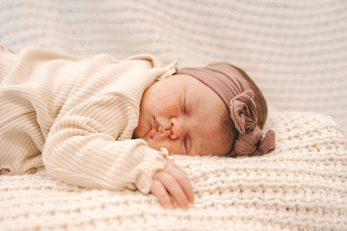 Newborn baby peacefully sleeping wrapped in a cream blanket, representing mil refuse baby name concerns in families.