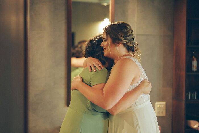 Bride hugging a woman indoors, capturing intimate wedding moments that turned out to be completely accurate.