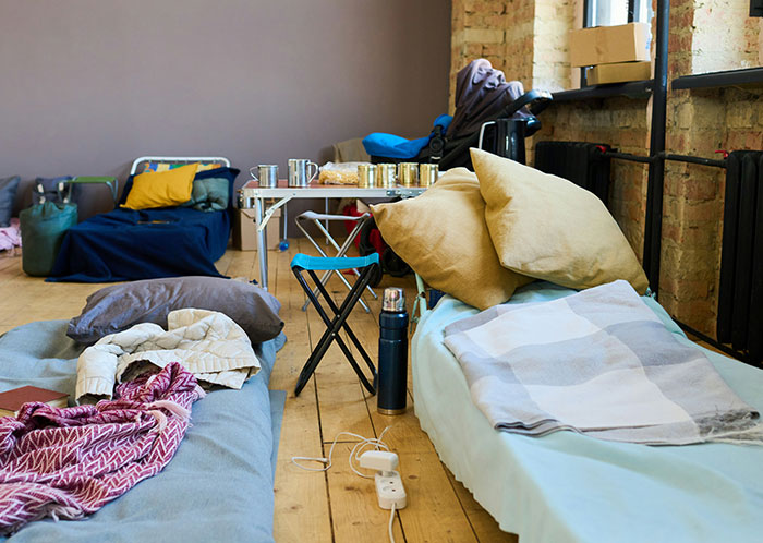 Sleeping area with makeshift beds and personal belongings illustrating homeless people’s horrifying experiences indoors.