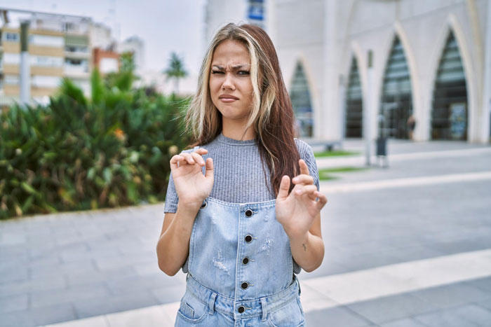 Young woman looking uncomfortable and hesitant outdoors, expressing child-loathing and refusal to be a free nanny. Young woman looking uncomfortable and hesitant outdoors, expressing child-loathing and refusal to be a free nanny.