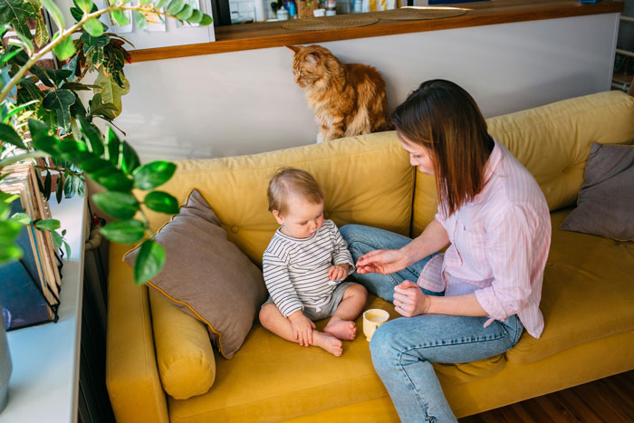 Woman with child on yellow sofa, illustrating child-loathing lady caring for toddler in a family home setting. Woman with child on yellow sofa, illustrating child-loathing lady caring for toddler in a family home setting.