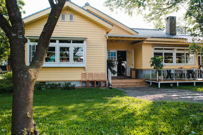 Yellow family home with porch and green lawn, representing inherited property amid mom's 37K debt and daughter's refusal to sell.