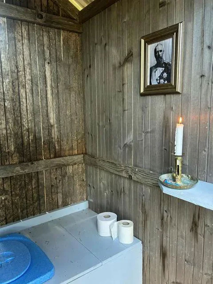 Rustic wooden interior with unique household items including toilet paper, a candle, and framed photo in a rare setting.