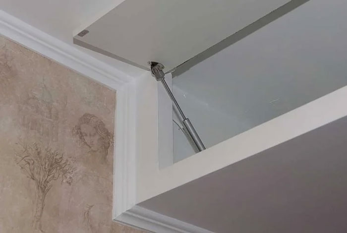 Close-up of a unique household item gas strut holding open a cabinet door, shared as a rare item in some countries.