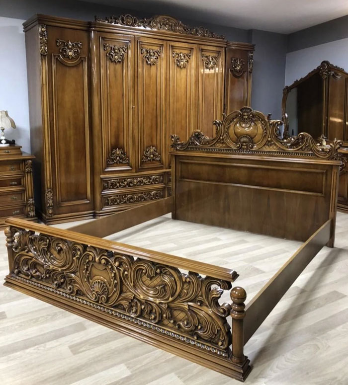 Ornate wooden bed frame and matching wardrobe with intricate carved household items unique to certain countries.