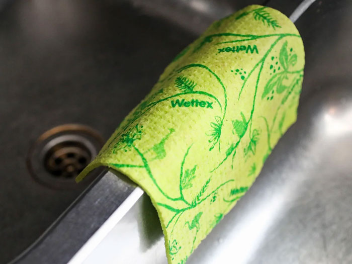 Green patterned Wettex cloth hanging on a sink faucet, a unique household item found in some countries only.