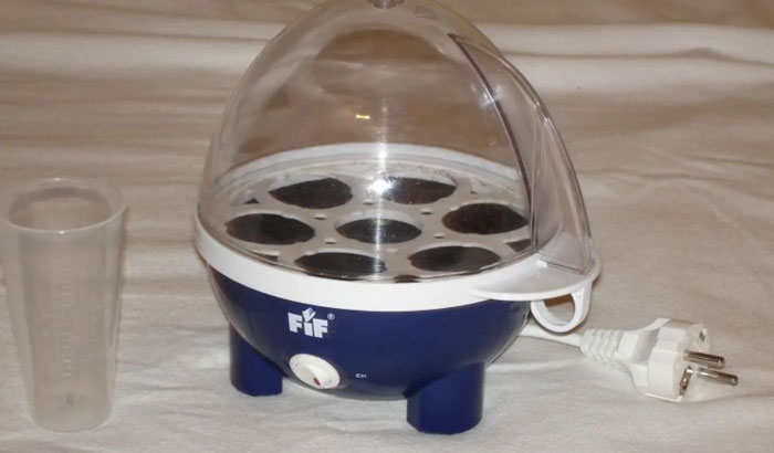 Egg cooker with transparent dome and measuring cup, a unique household item found in some countries only.