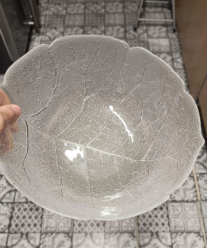 Hand holding a transparent leaf-patterned bowl, a unique household item found in some countries only.